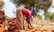Woman collecting baked bricks to build home in Burundi
