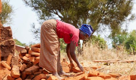 Woman collecting baked bricks to build home in Burundi