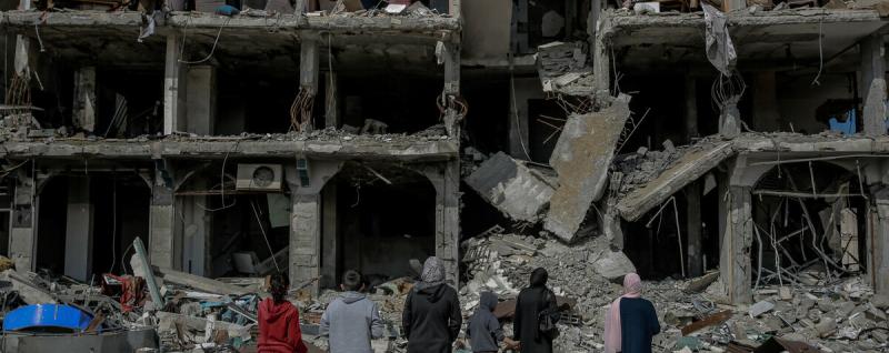 Individuals look at ruins from missiles